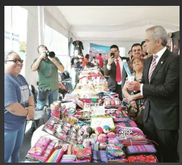 Mercado artesanal con representantes institucionales recorriendo exposición textil